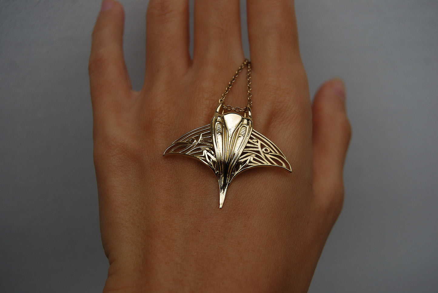 Close-up of gold manta ray pendant, highlighting ocean-inspired jewelry texture and finish