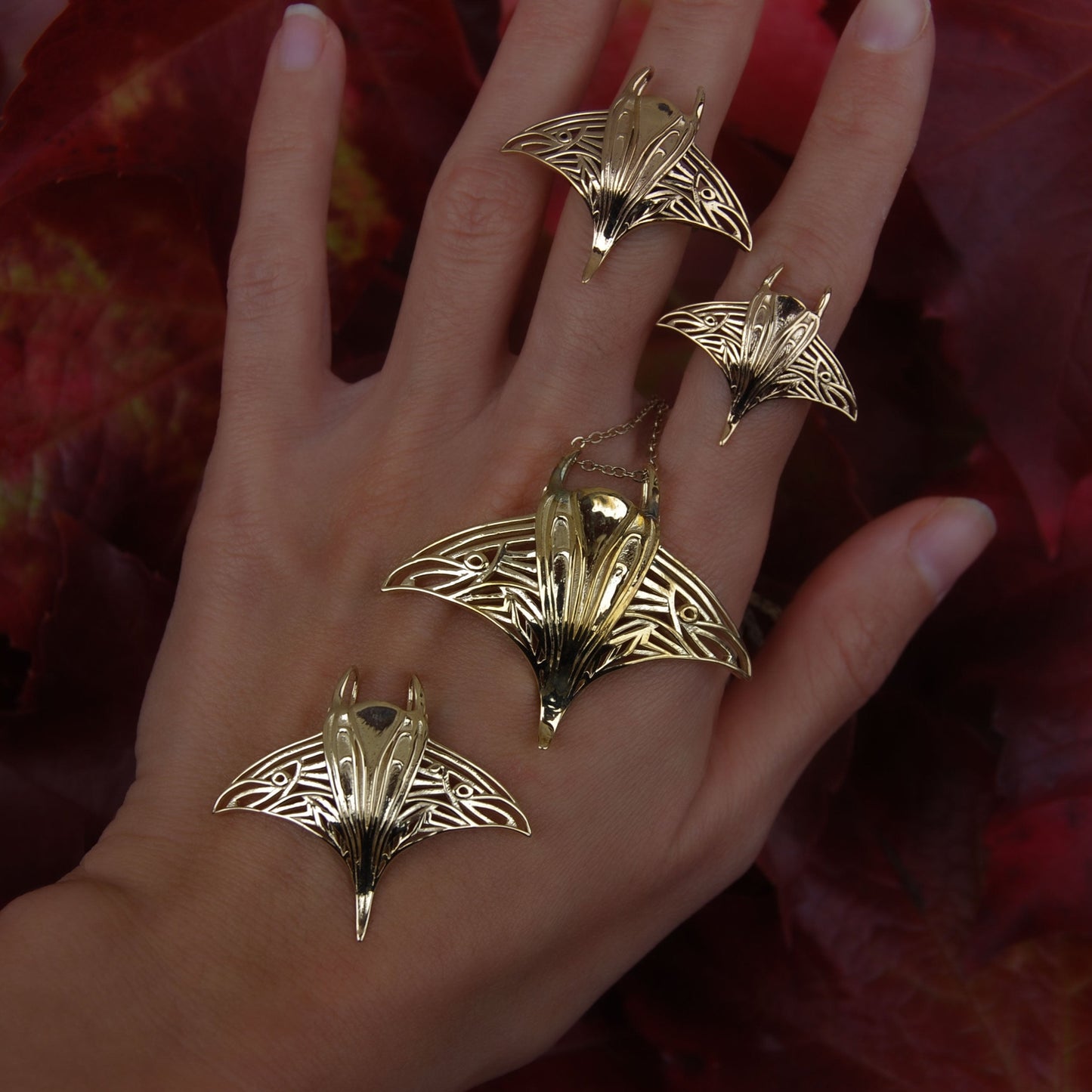 Hand wearing gold manta ray pendant and matching ring, featuring handcrafted ocean jewelry.
