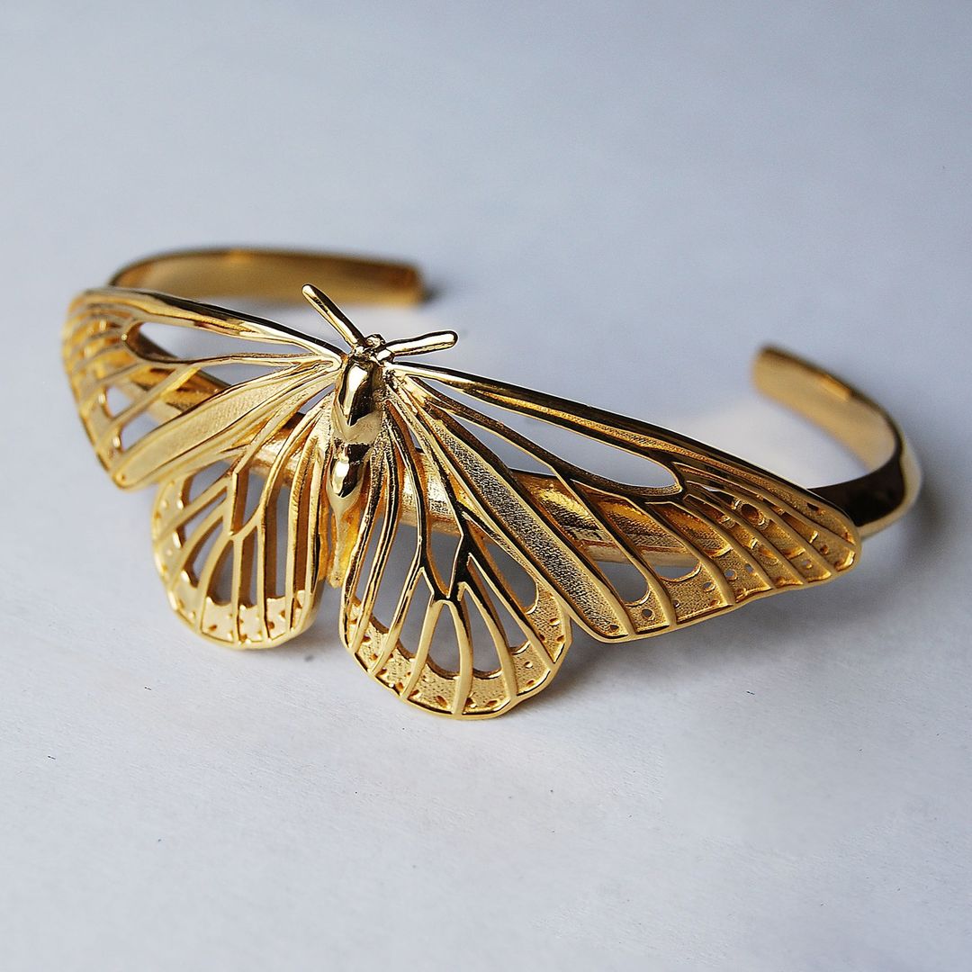 Side view of 14K gold-plated Monarch Butterfly Bracelet on white background, emphasizing wing texture and polished finish.