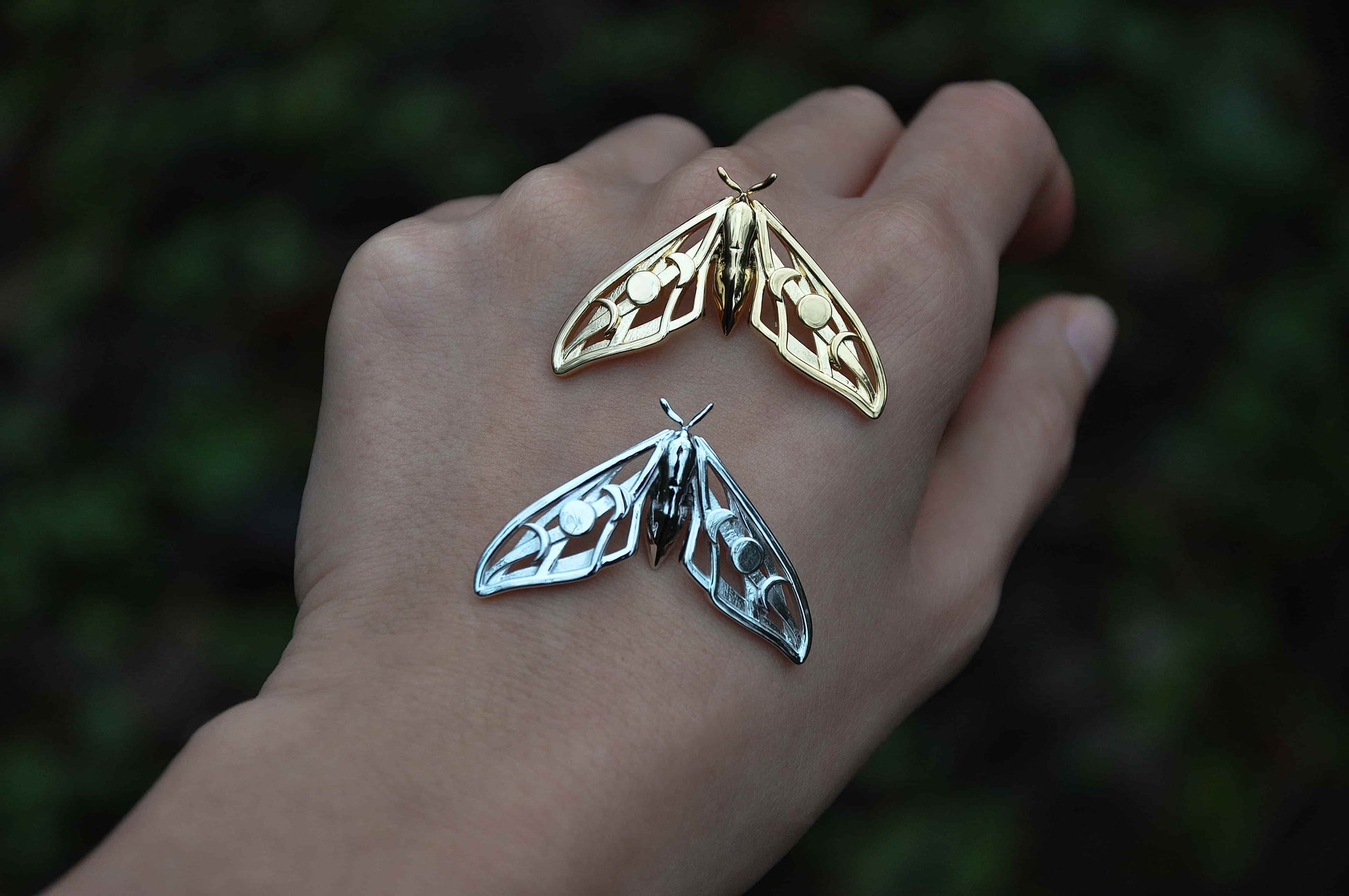 Celestial Hawk Moth Pendants in gold and silver side by side, emphasizing material contrast and ethereal design.