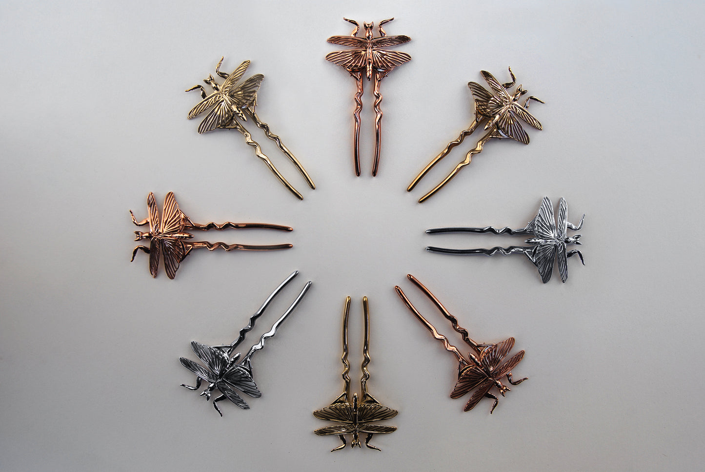 Display of handmade orchid mantis pins on white background