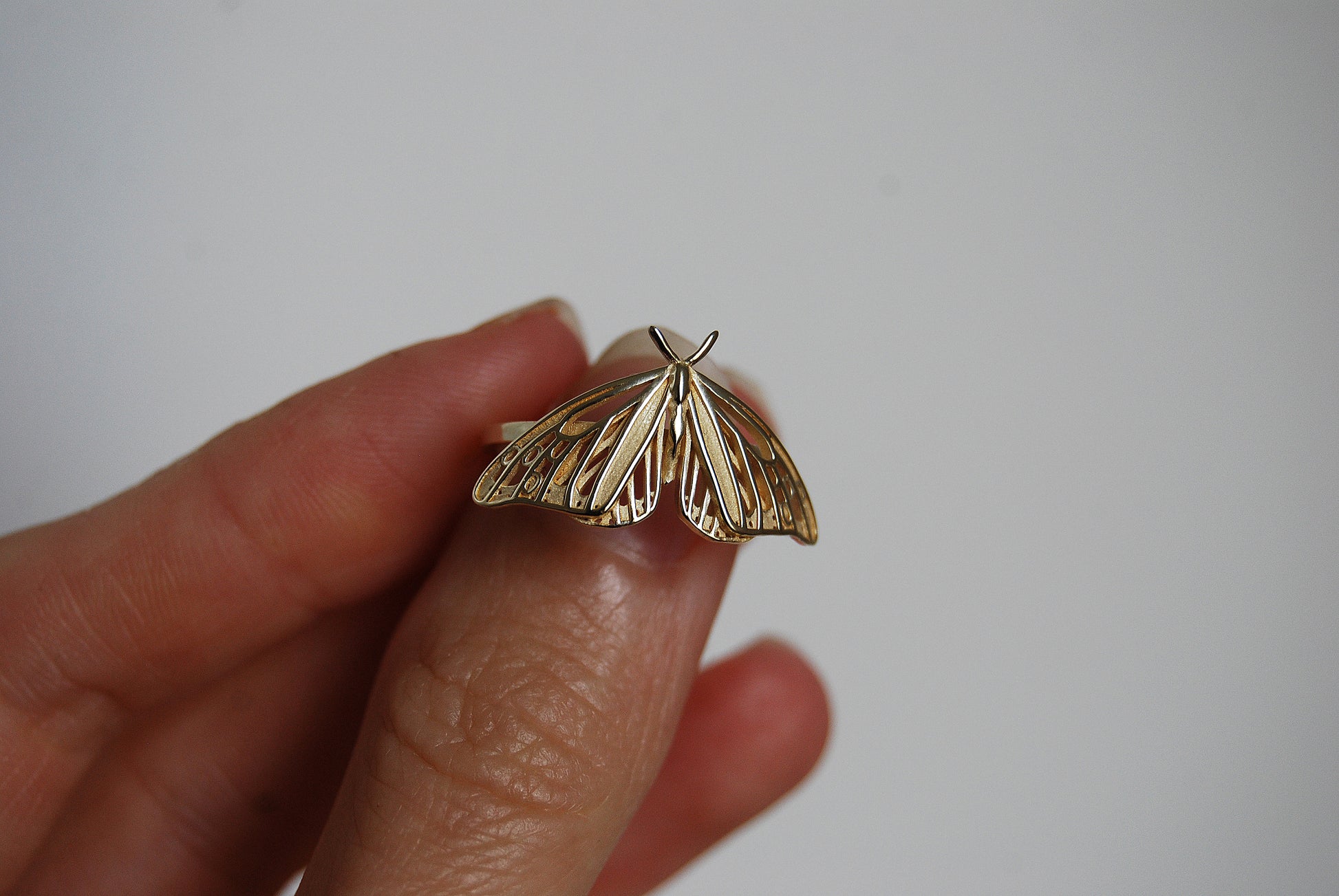 Hand holding a Monarch Butterfly ring with intricate Art Nouveau inspired design