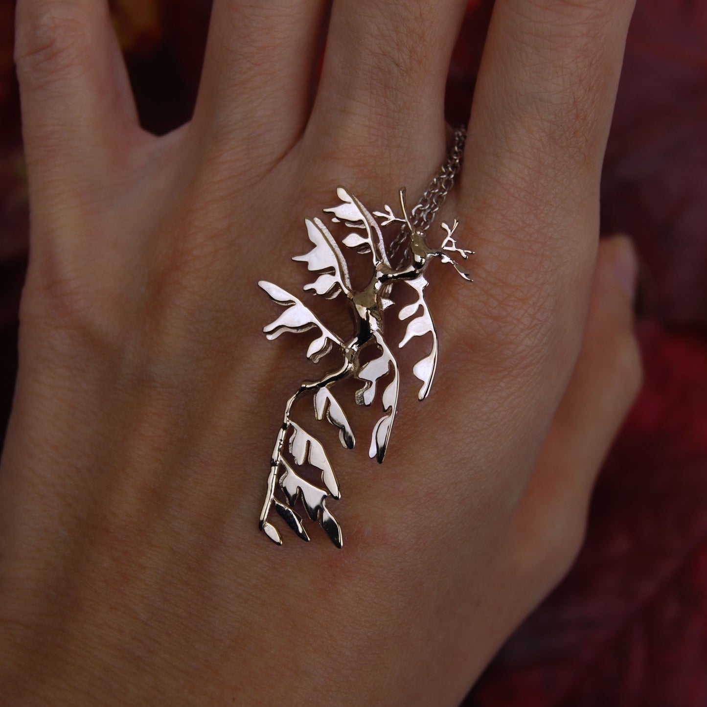 Sterling silver Leafy Sea Dragon Pendant worn on hand, showcasing ocean-inspired jewelry.