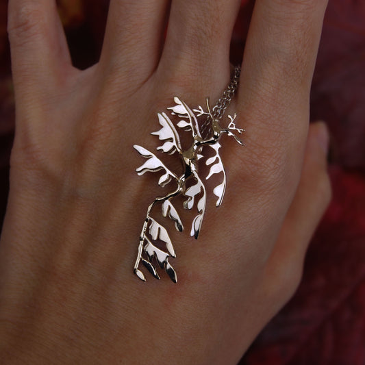 Sterling silver Leafy Sea Dragon Pendant worn on hand, showcasing ocean-inspired jewelry.