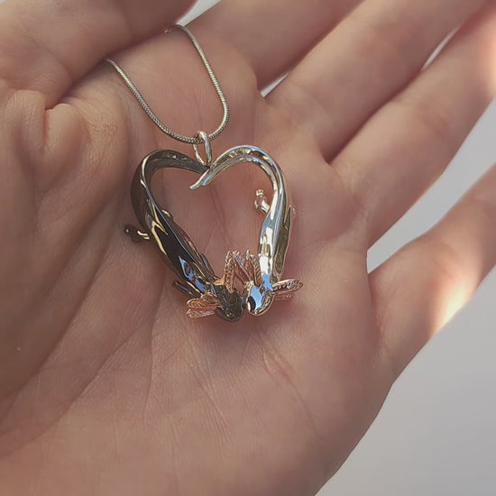 Video showing the Exolotl Love Pendant held from the front, rotating to reveal the contrast between the polished silver and black rhodium axolotls forming a heart.