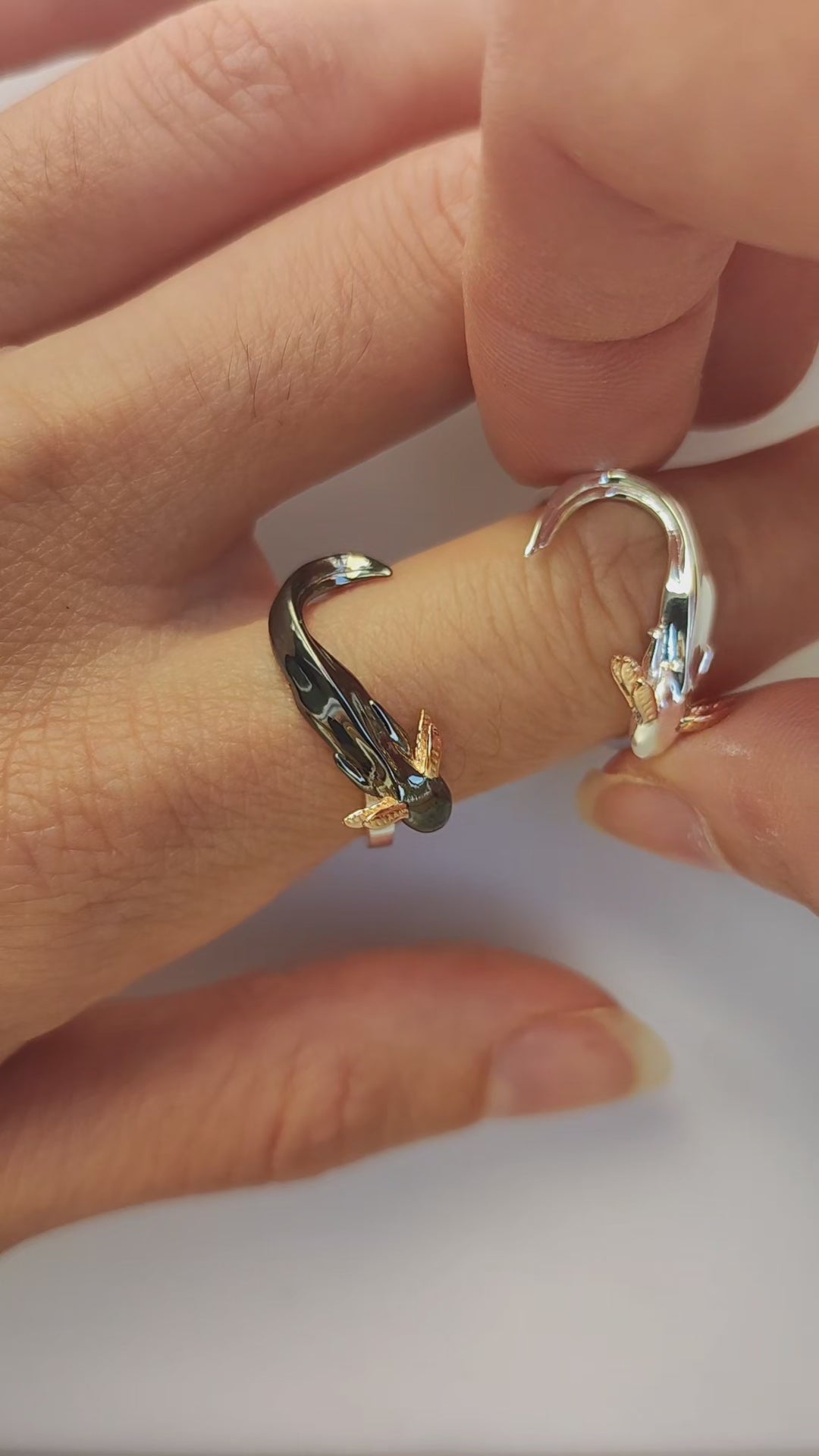 Step-by-step front view of wearing the handcrafted Axolotl stacking ring set — individual sterling silver and black rhodium axolotl rings with 14k rose gold gills are layered to gradually form a heart shape with their intertwined tails