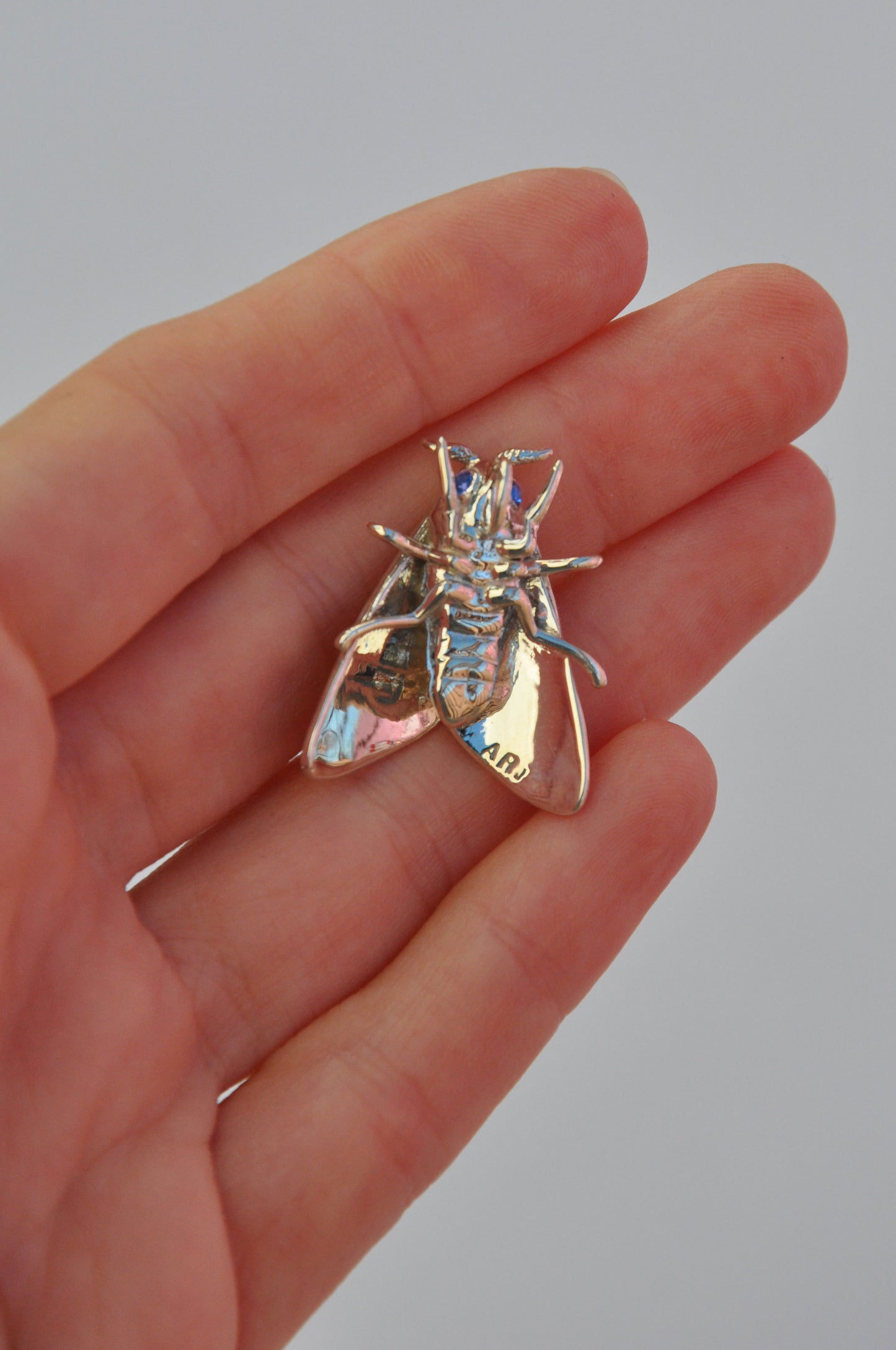 Right side view of Rosy Maple Moth pendant in sterling silver with enamel and gemstone accents