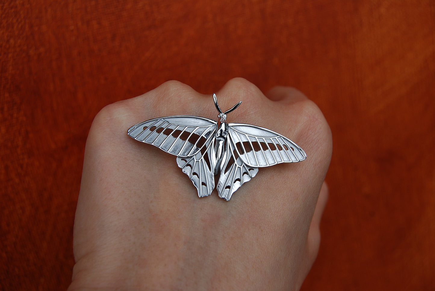 Sterling silver Blue Triangle Butterfly pendant photographed in nature, front view showing vibrant wing contours.