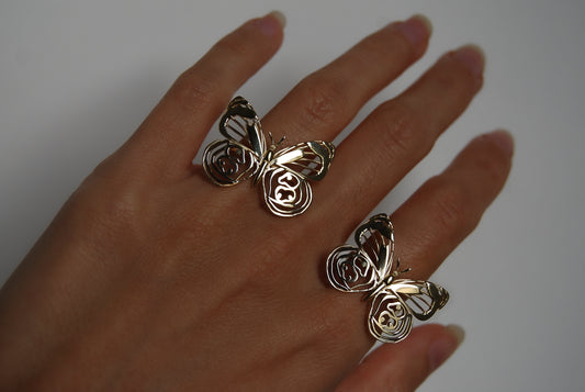 Hand wearing two sterling silver butterfly rings, showcasing delicate wing detail and handcrafted design.