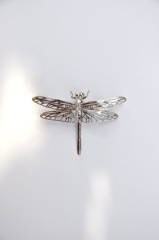 Silver dragonfly brooch on a white background, highlighting its delicate wings and handcrafted detail.