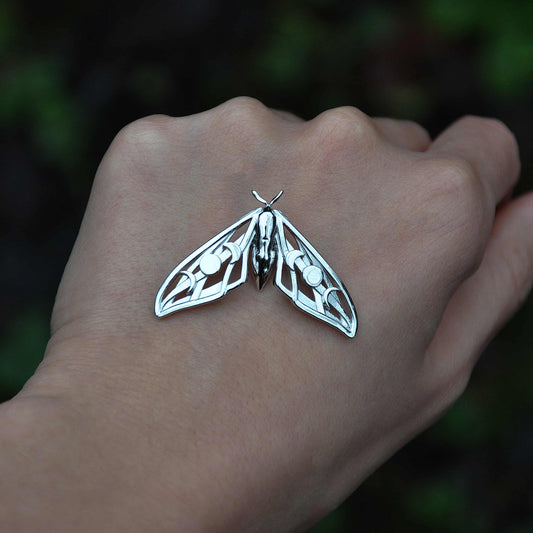 Front view of the Elestial Hawk Moth Pendant in sterling silver, showcasing embossed moon phases and delicate wing cut-outs.