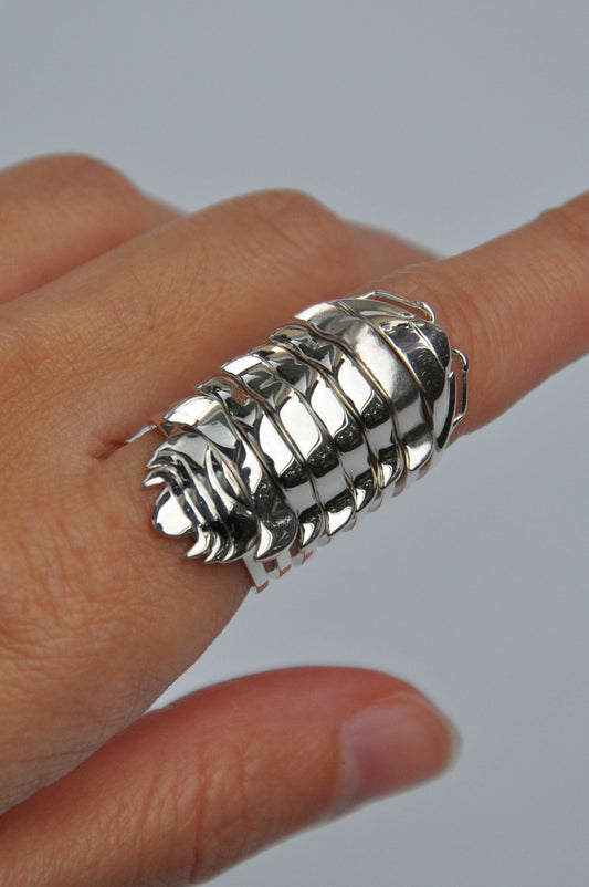 Hand wearing stacked silver isopod rings inspired by segmented armor and fossil design.