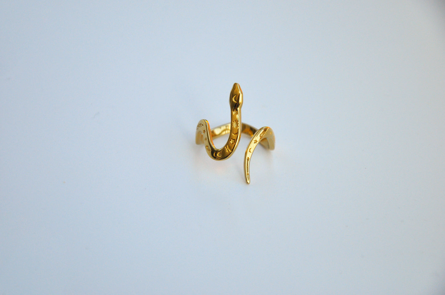 Front view of celestial snake ring in gold on white background, showing serpent head and celestial motifs.