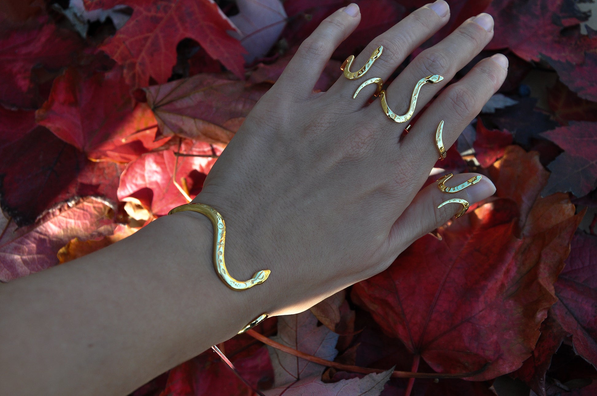 Multiple celestial snake rings stacked on hand, showcasing layered styling and symbolic serpent jewelry.
