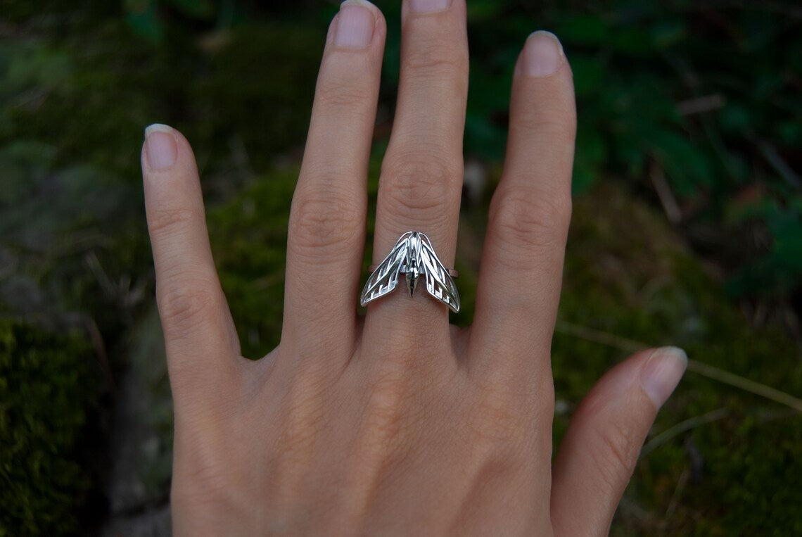 Single sphinx moth ring in sterling silver worn on hand, emphasizing delicate insect-inspired design.