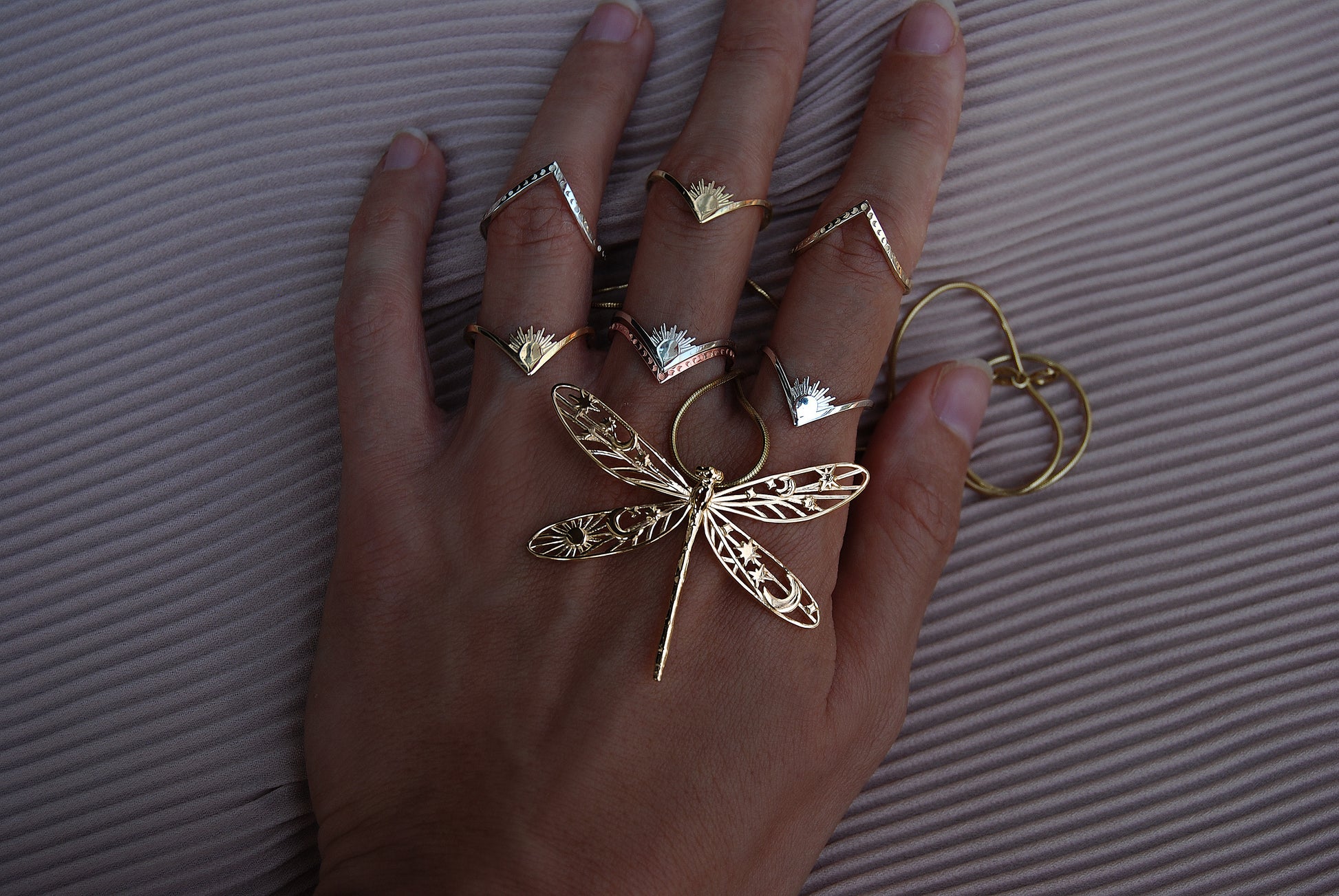 Stacking rings featuring celestial motifs and a damselfly design, blending nature and cosmic symbolism in handcrafted jewelry.