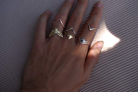 Sun and moon chevron rings stacked with moth ring on hand, showcasing celestial jewelry styling.