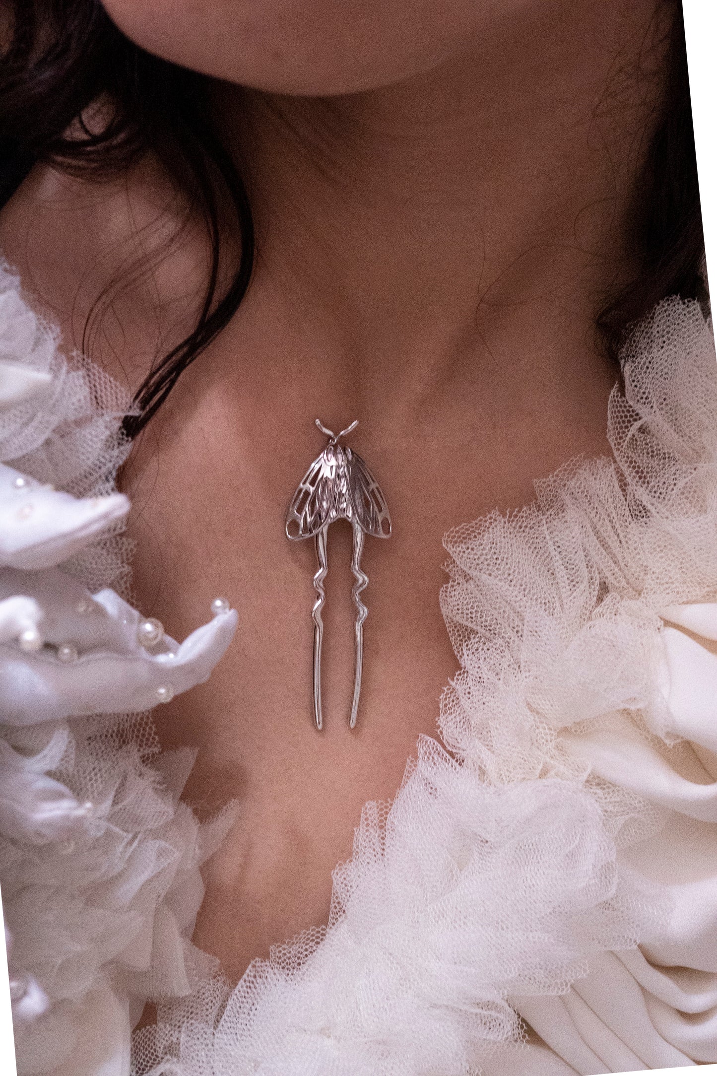 Model holding a rhodium silver Tiger Moth hair pin, showcasing handcrafted insect-inspired jewelry with folded wing details and a polished metallic finish.