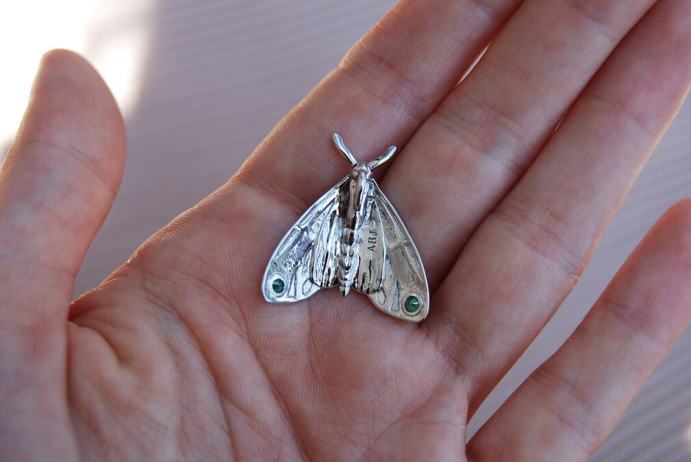 Back view of Tiger Moth pendant held in hand