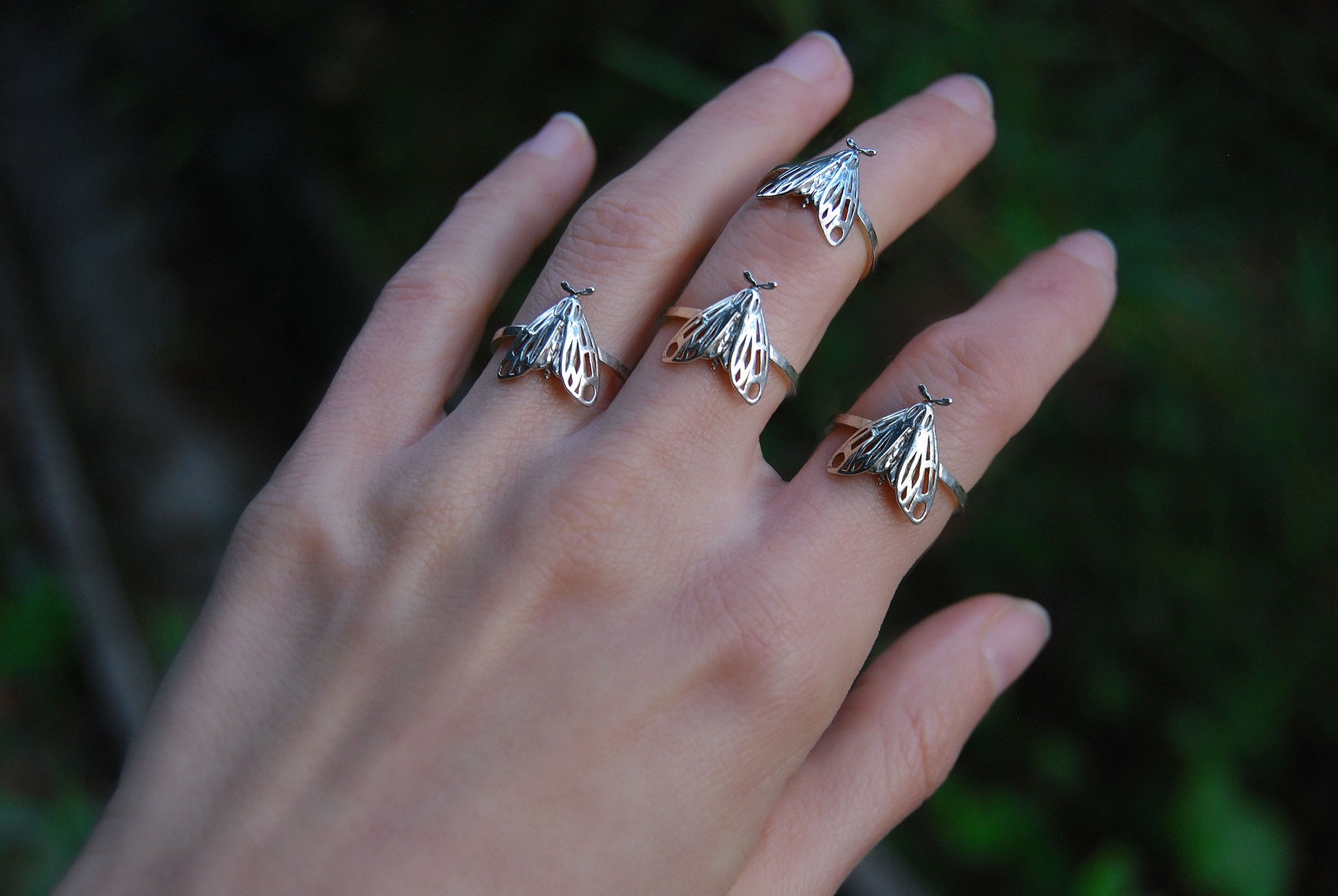 Multiple sterling silver Tiger Moth Rings stacked on hand, styled as layered bug jewelry.