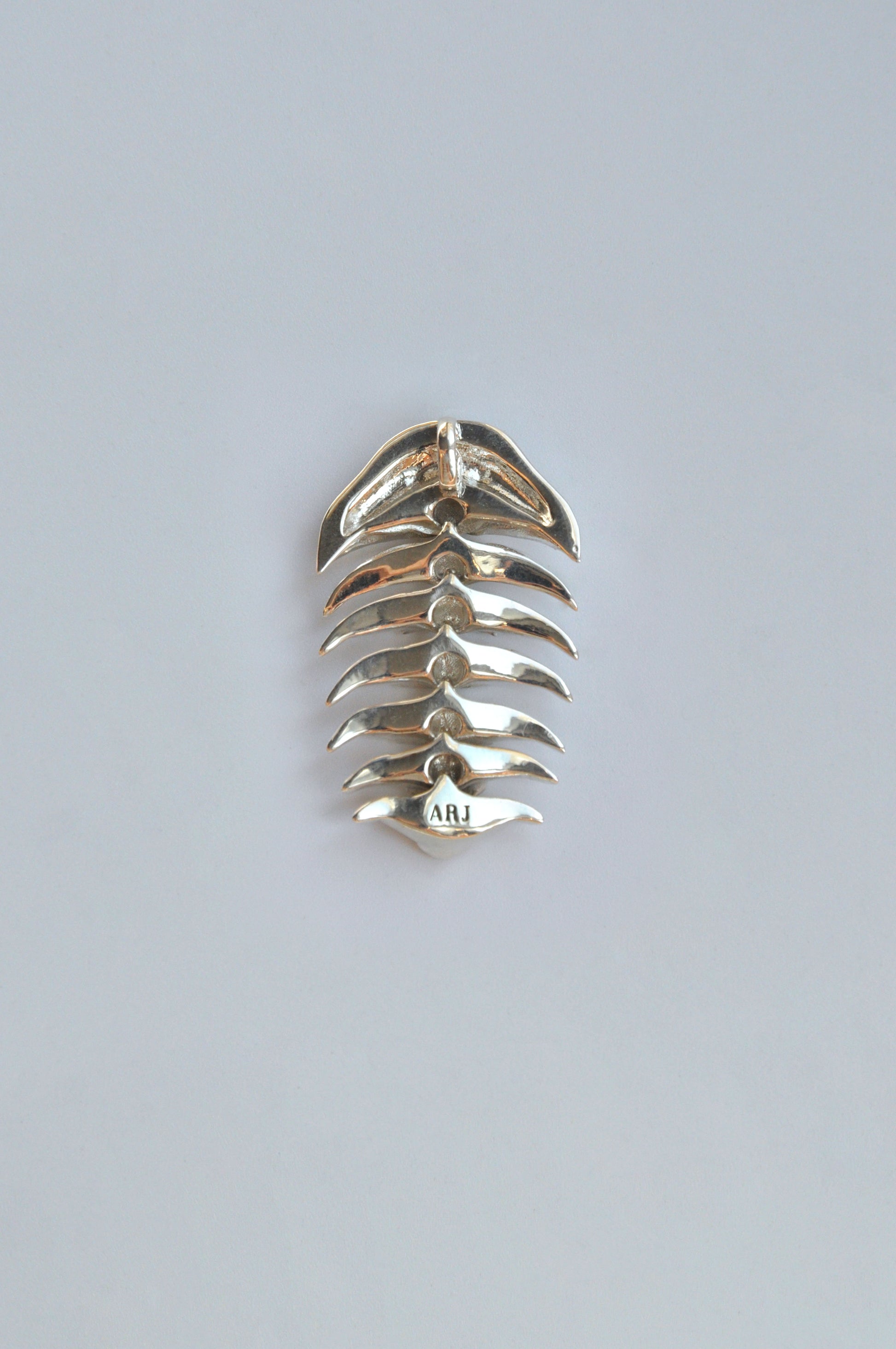 Back view of the sterling silver articulated trilobite pendant on a white background. The reverse side showcases the smooth, polished backing and subtle contours of the segmented design, emphasizing craftsmanship and structural integrity.