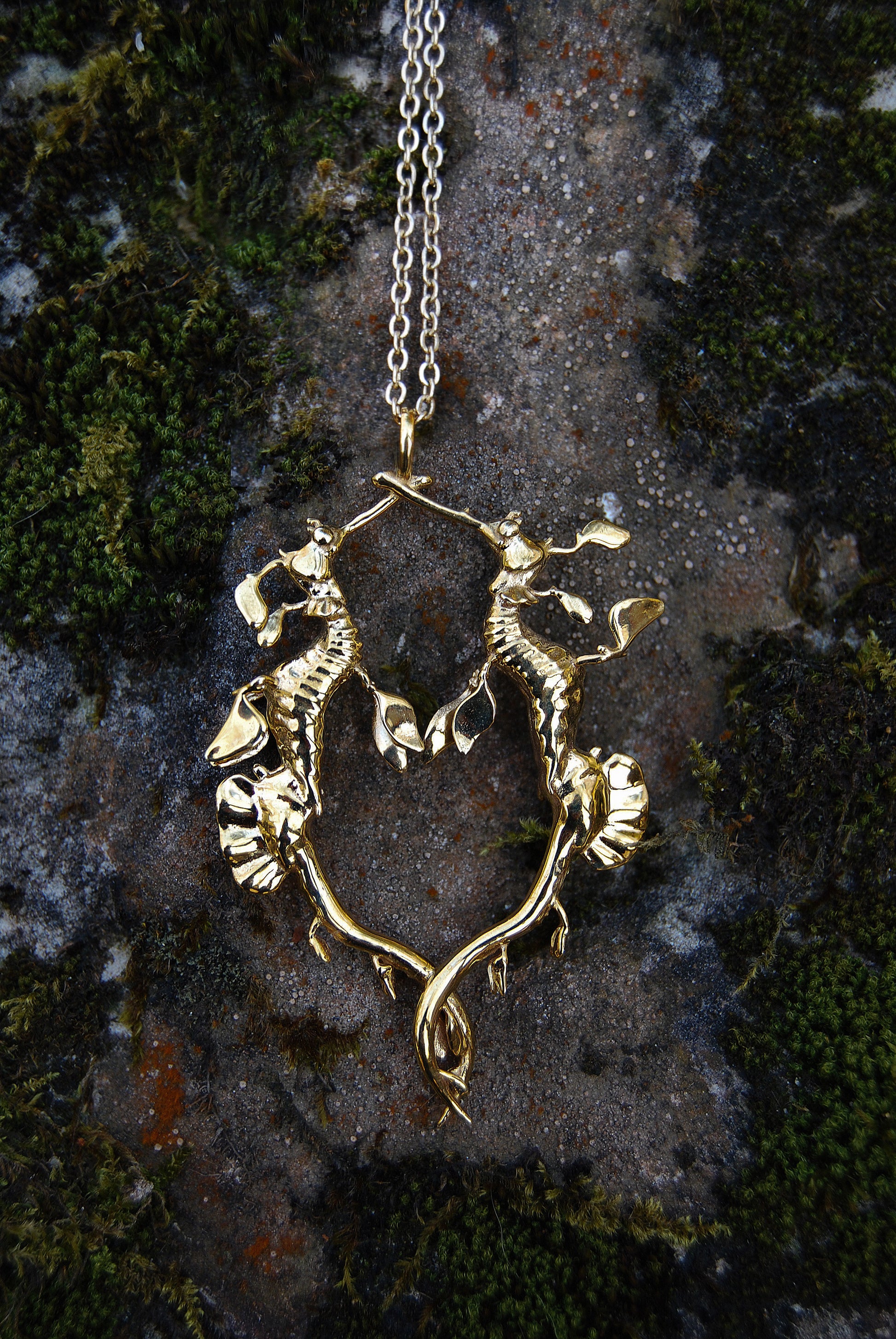 Gold Weedy Sea Dragon Pendant styled on stone background, highlighting sculptural sea creature detail.