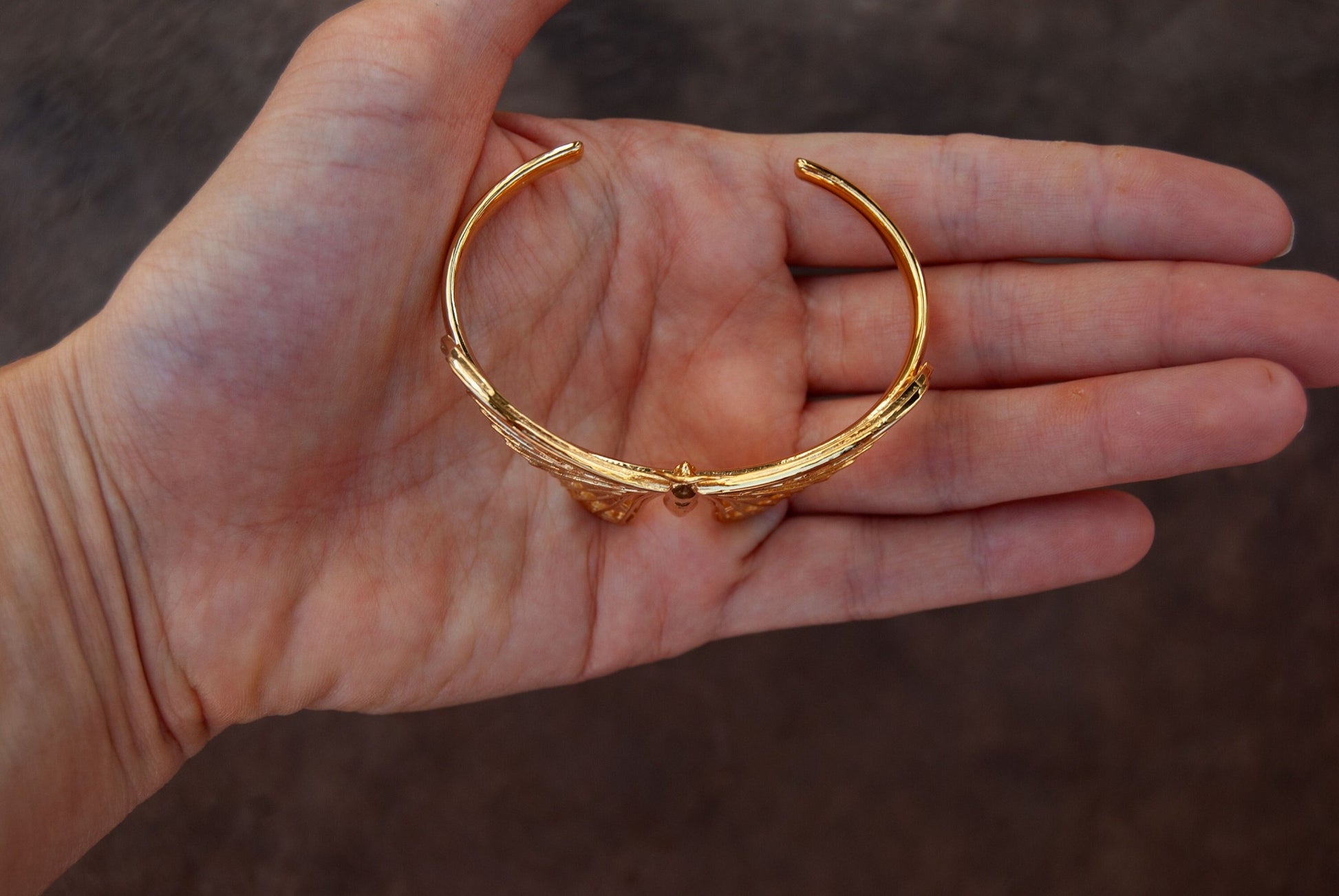 Top view of 14k gold plated Atlas moth bracelet with intricate wing design on white background