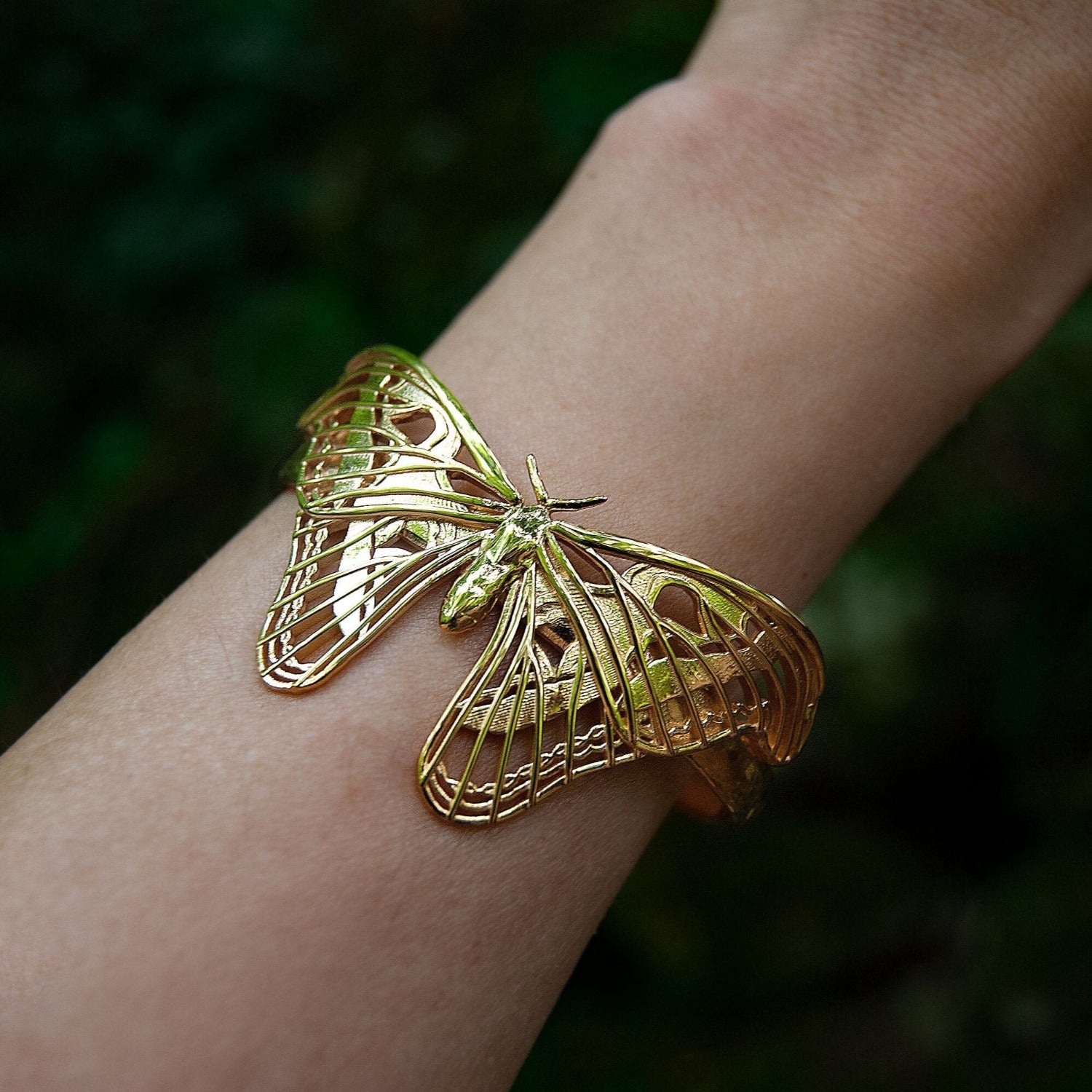 Close-up of the Atlas Moth Bracelet in 14k gold-plated brass, highlighting the intricate wing details and sculptural contours of the moth design. The polished gold surface catches the light, emphasizing the craftsmanship and elegance of this nature-inspired cuff.