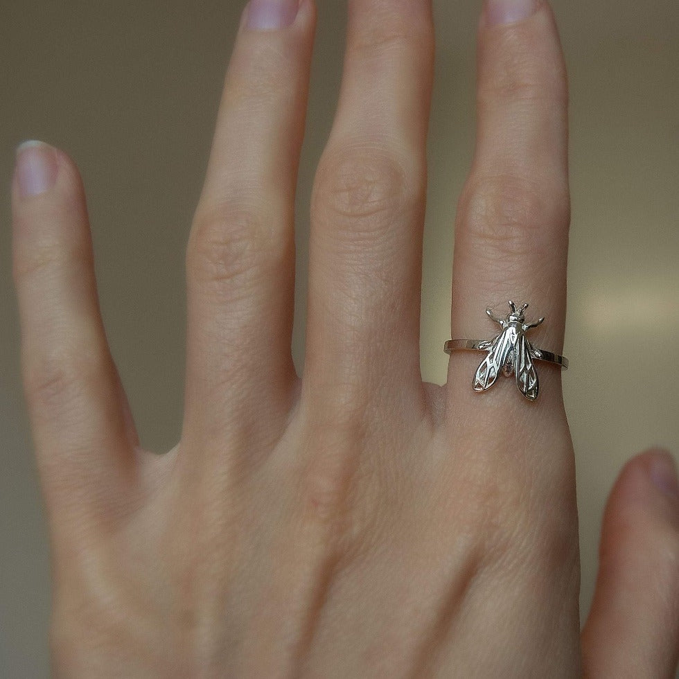 Custom handmade bug ring with artistic details placed on a marble slab.