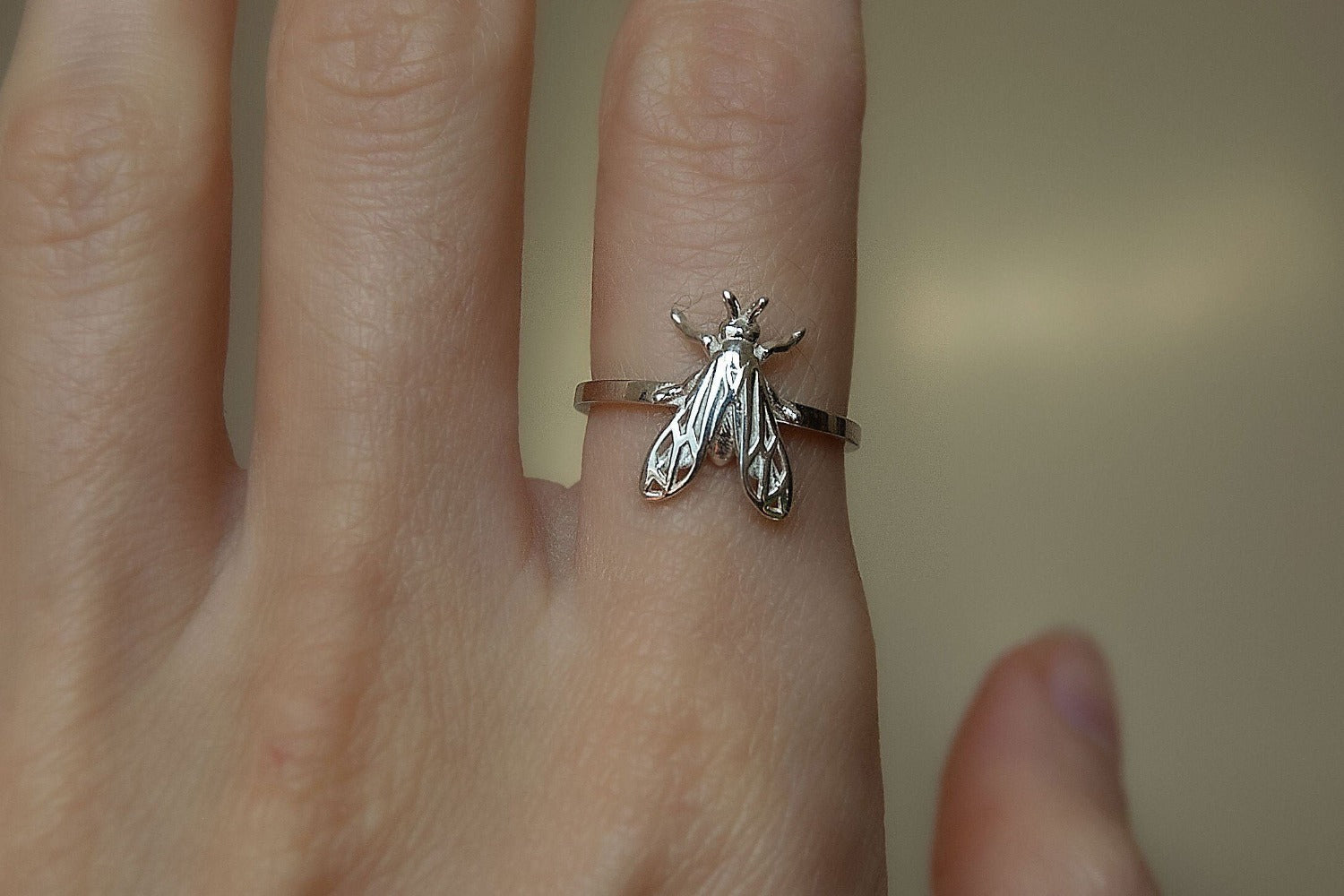 Polished silver wasp-inspired band displayed on a black velvet cushion.