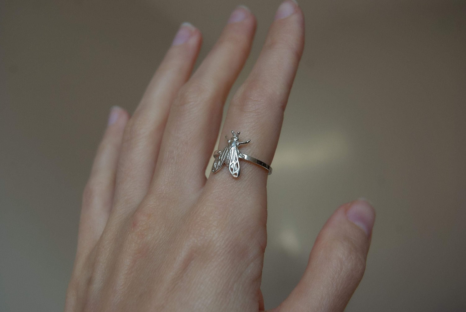 Silver bee ring worn on a finger showing intricate craftsmanship and size.