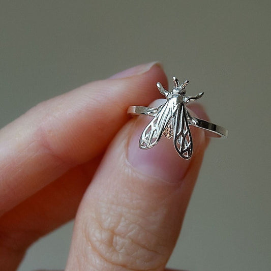 Close-up of a silver bee wasp ring showing detailed wings and body texture.