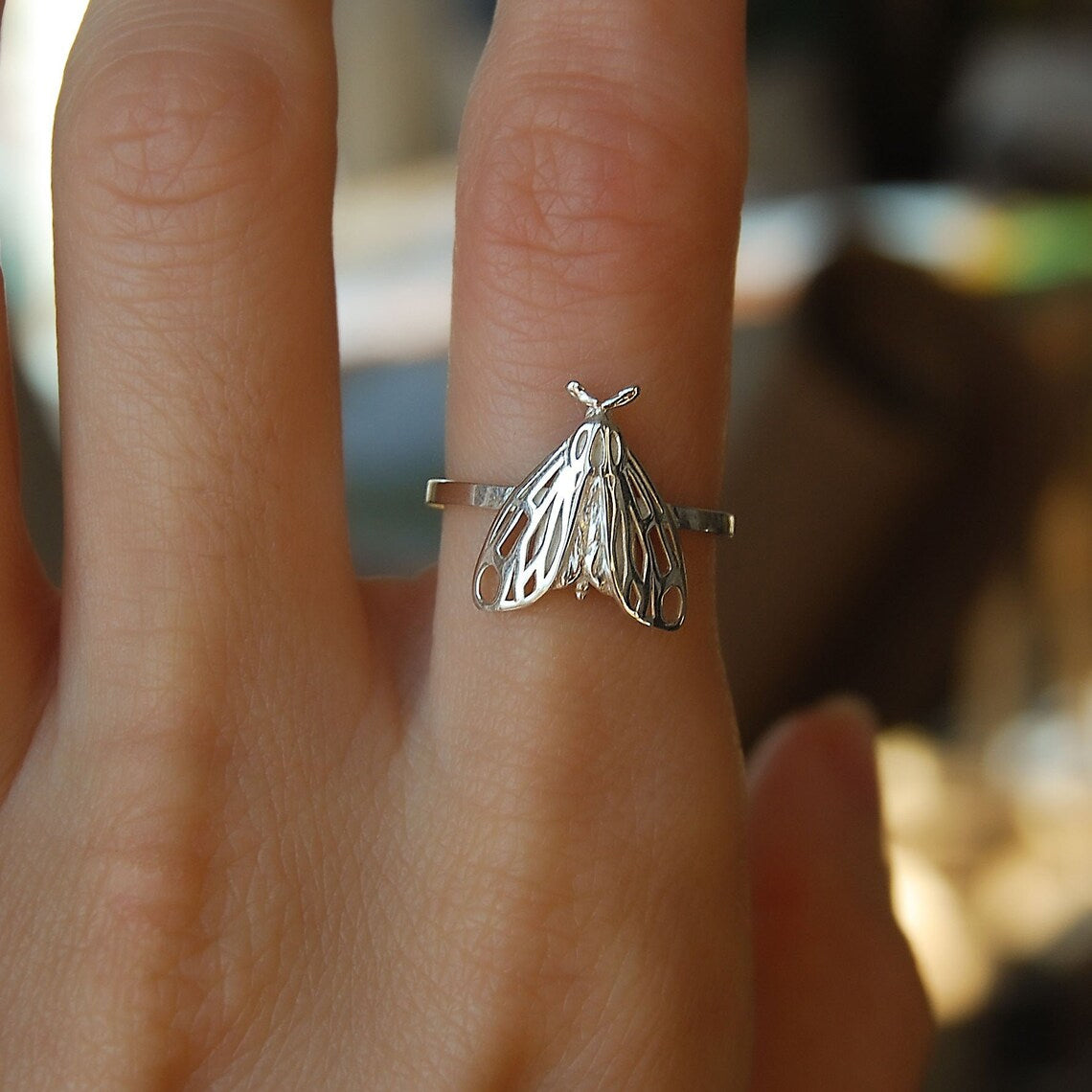 Sterling silver Tiger Moth Ring worn on finger, showcasing delicate moth design and polished finish.