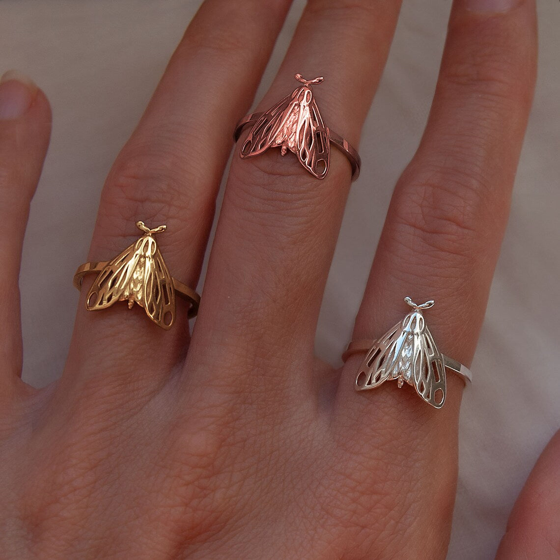 Tiger Moth Rings in sterling silver, 14K gold plated, and 14K rose gold plated finishes worn on finger.