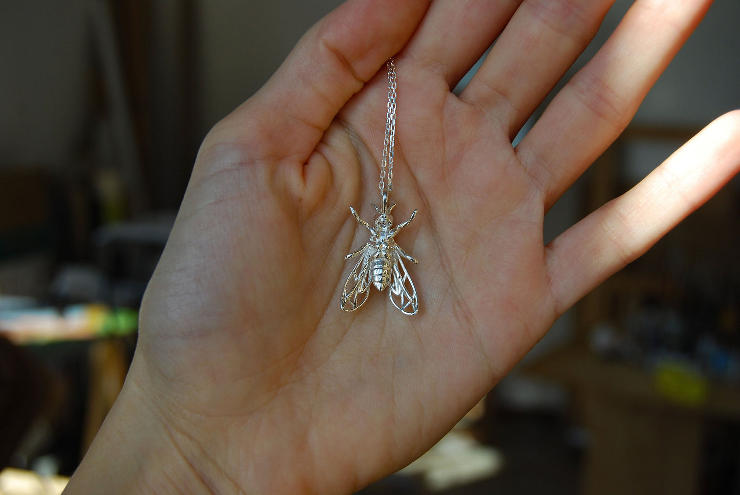 Back view of wasp pendant on hand, highlighting craftsmanship of insect necklace
